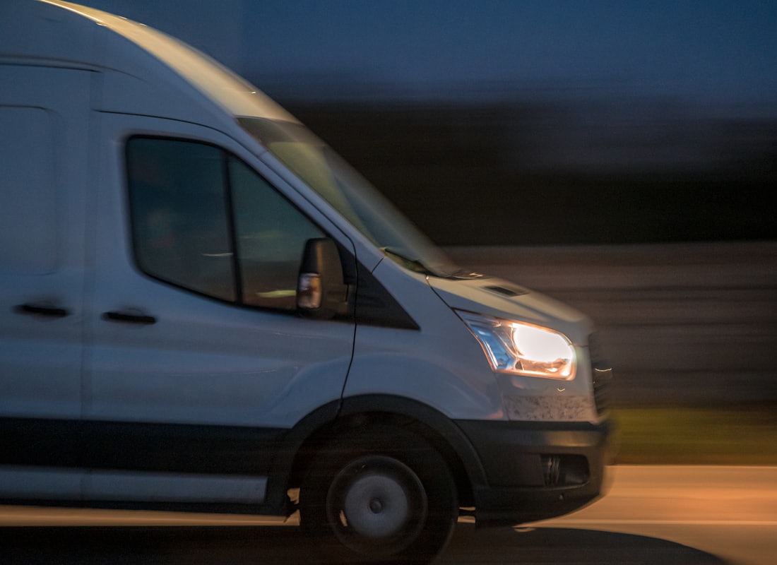 High-roof cargo van running at night with headlights on